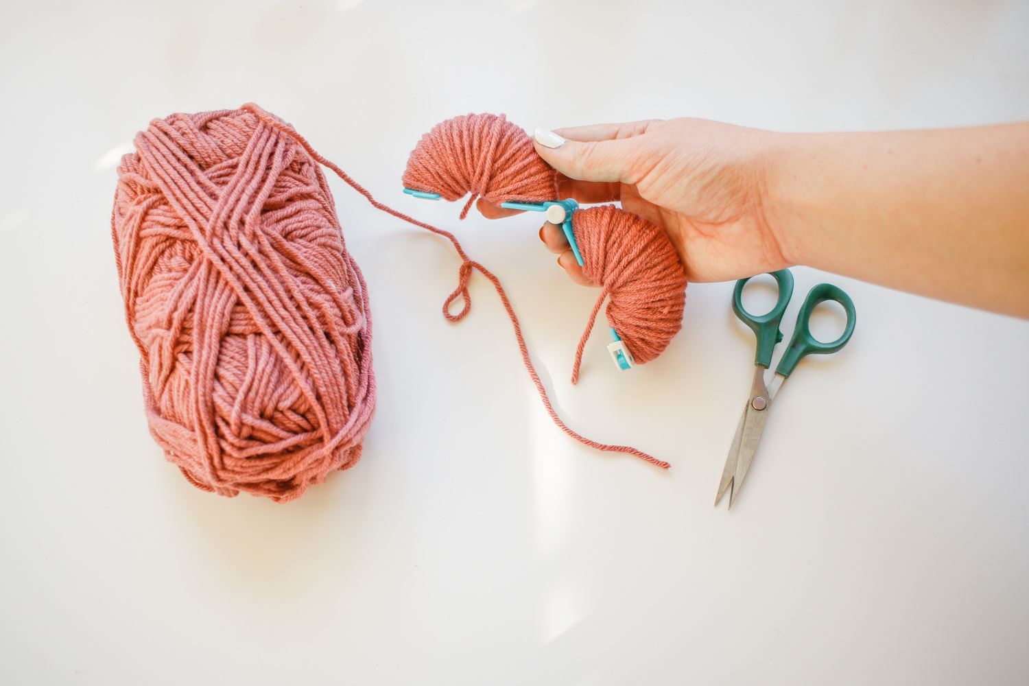 Wrap yarn around each side of pompom maker